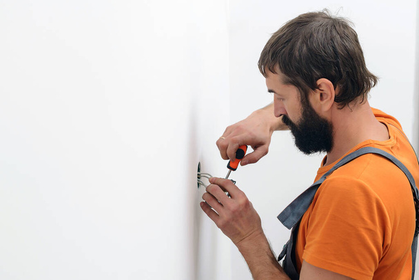 Man installing light switch after home renovation. Electrician mounting electric sockets on the white wall. Electrician wiring a new build. Worker installing socket in new house. - Fotografie, Obrázek