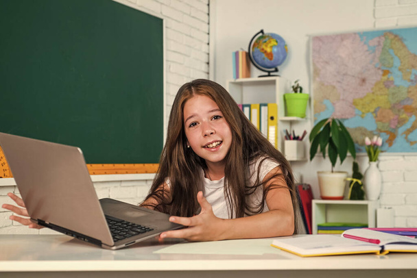 Cute teen child near chalkboard with laptop on online lesson, back to school - Foto, Bild
