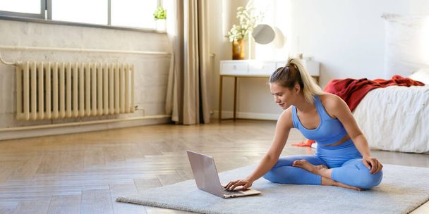 Young woman preparing for a home workout under the guidance of an online instructor. - Zdjęcie, obraz
