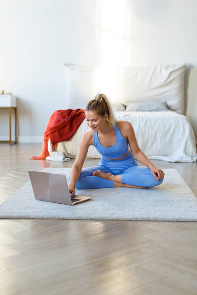 Vertical photo of a young woman preparing for a home workout under the guidance of an online instructor. - Photo, Image