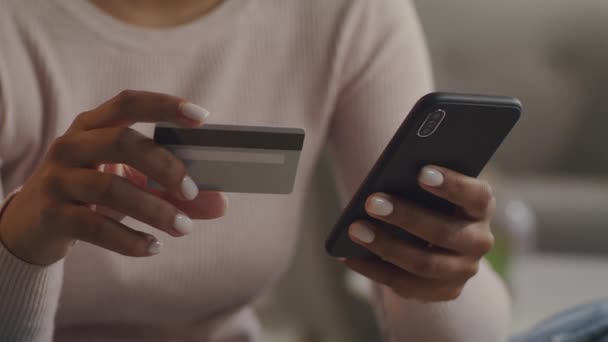 irreconocible señora afroamericana de compras en la aplicación móvil, la introducción de datos personales de la tarjeta de crédito en el teléfono inteligente - Metraje, vídeo