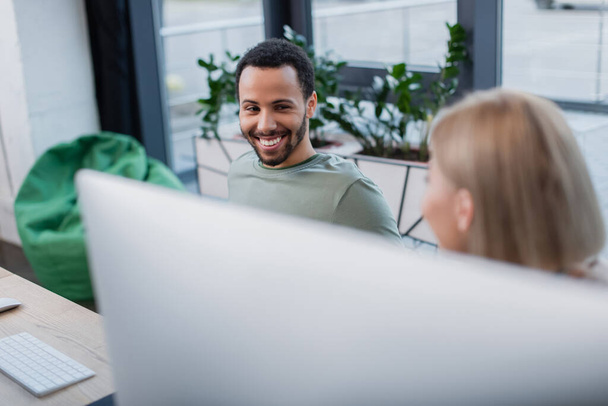 happy african american man looking at blonde colleague in office  - Photo, Image