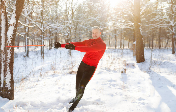 Γυμναστική λειτουργικότητας. Πλήρες μήκος του ώριμου ανθρώπου χρησιμοποιώντας ιμάντες αντίστασης του σωματικού βάρους στο δάσος το χειμώνα, αντίγραφο χώρο - Φωτογραφία, εικόνα