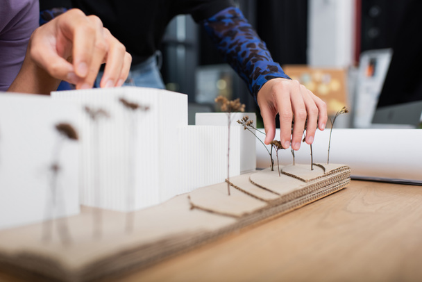 Masanın üzerinde ev modelinin yanındaki mimarların kırpılmış görüntüsü - Fotoğraf, Görsel