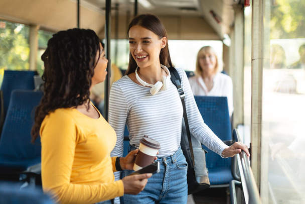 Весёлые мультиэтнические улыбающиеся женщины, стоящие в автобусе и разговаривающие - Фото, изображение