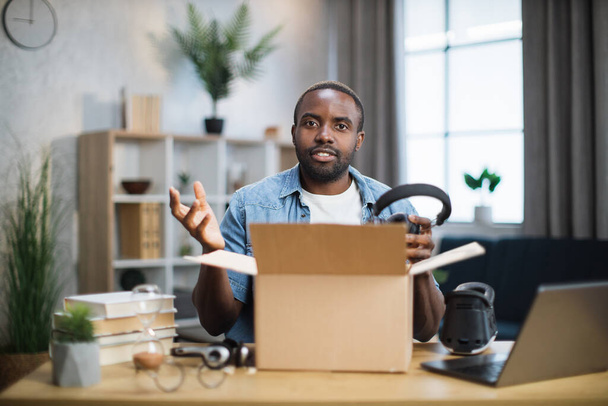 Man sitting at the table at home unpacking box with headphones - Photo, image