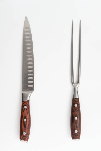 Vleessnijmes en vorkset met houten handgrepen op een witte achtergrond - Foto, afbeelding
