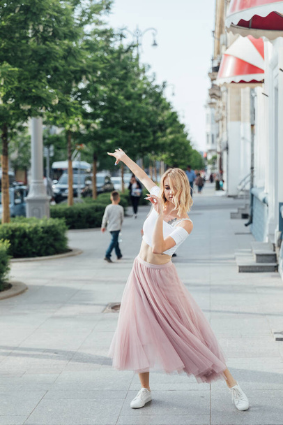 beautiful woman dancing to music on the street of the city - Фото, зображення
