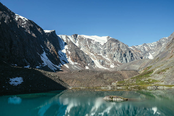 Luminen vuori heijastuu kirkkaassa vedessä jääkauden järvi. Kaunis aurinkoinen maisema, jossa jäätikkö heijastus veden pinnalla vuoren järven kirkkaan taivaan alla. Lumi kallioilla näkyy vuoristojärvessä. - Valokuva, kuva
