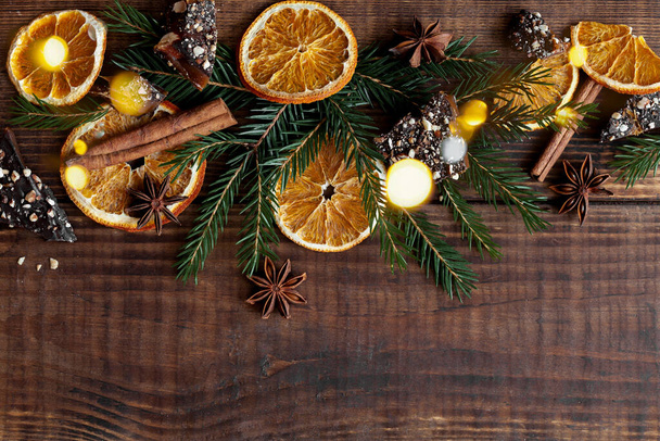 Wooden christmas background with oranges, fir branches, cinnamon and chocolade. Winter cozy background, top view - Φωτογραφία, εικόνα