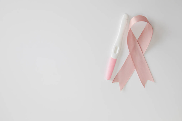 Ruban rose de sensibilisation au cancer du sein satiné avec test de grossesse à blanc isolé sur fond blanc - Photo, image