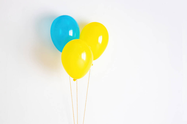 Κίτρινο με μπλε μπαλόνι. Κίτρινο και μπλε εορταστικό, χαρούμενο μπαλόνι σε σπάγκο.  - Φωτογραφία, εικόνα