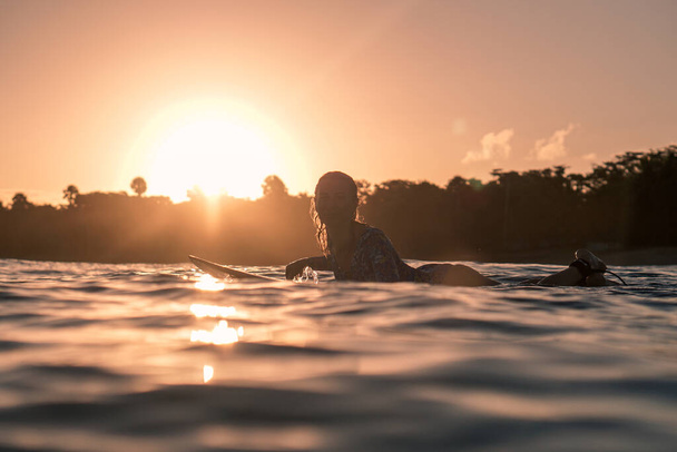 Portrait of blond surfer girl on white surf board in blue ocean pictured from the water at golden sunrise time in Encuentro beach in Dominican Republic - Foto, imagen