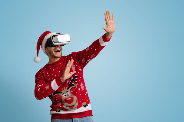 Holiday Entertainment. Man in santa hat using VR headset, experiencing virtual reality - Fotoğraf, Görsel