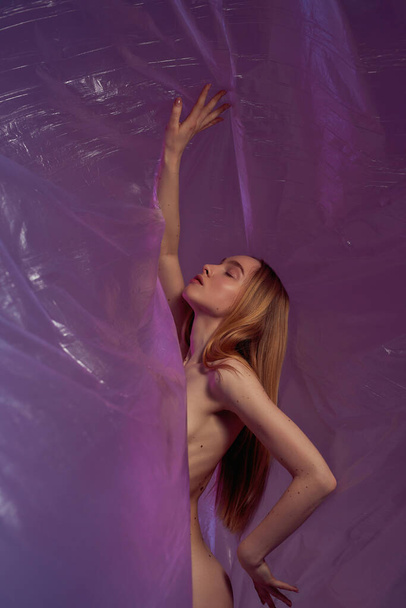 Caucasian nude girl posing in transparent oilcloth - Foto, afbeelding