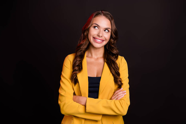 Photo of adorable dreamy young lady wear yellow jacket smiling arms crossed looking empty space isolated black color background - Φωτογραφία, εικόνα