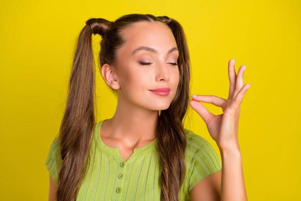 Portrait of attractive dreamy funny girl tasting invisible dish isolated over vibrant yellow color background - Foto, Imagem