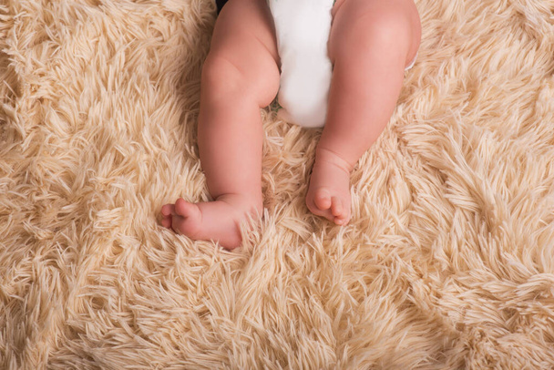 Γυμνά πόδια νεογέννητου σε αφράτο, ελαφρύ, ένα τόνο, ζεστό κάλυμμα. Χαριτωμένο νεογέννητο μωρό πόδια κοντά - Φωτογραφία, εικόνα