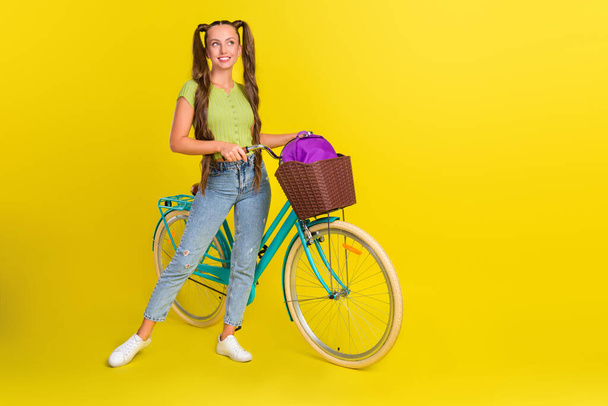 Full length body size view of attractive funny cheerful girl walking bicycle rest free time isolated over bright yellow color background - Fotó, kép