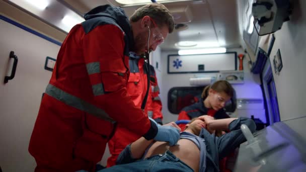 Multi-etnische paramedici die eerste hulp verlenen aan de mens in een noodvoertuig - Video