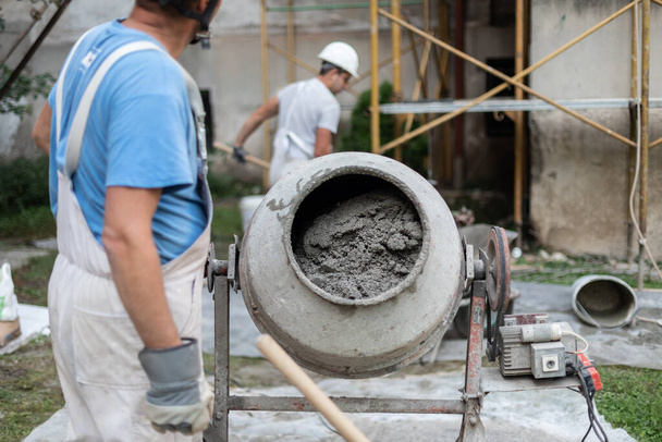 Labore worker operating concrete cement mixer at construction site. - Photo, Image