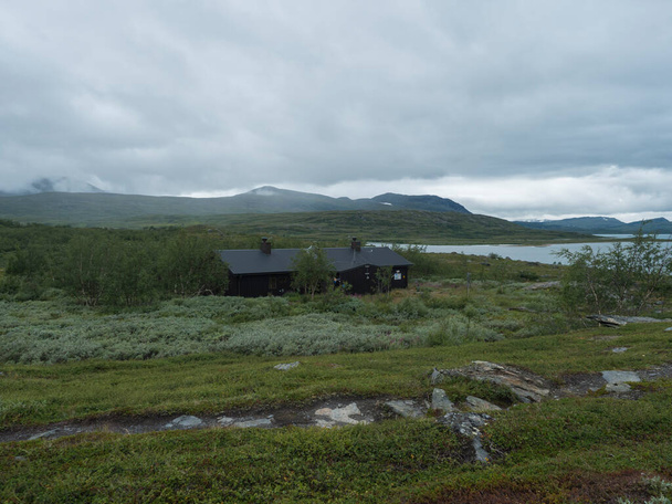 Lapland landscape at Virihaure lake with sami village Staloluokta houses and cottage, snow capped mountains and birch trees. Sweden summer moody and foggy wild nature, Padjelantaleden hiking trail. - Photo, Image