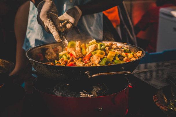 Aşçı, Slovenya 'nın Ljubljana kentinde düzenlenen Uluslararası Odprta kuhna Sokak Yemekleri Festivali' nin sokak tezgahında uluslararası füzyon füzyonu pişirdi. - Fotoğraf, Görsel