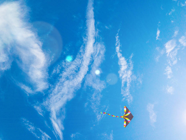 Kite blue sky. Colorful high flying toy. Air kite fly on wind clouds. Rainbow kite in summer background. Concept of dreams, freedom, childhood - Photo, Image
