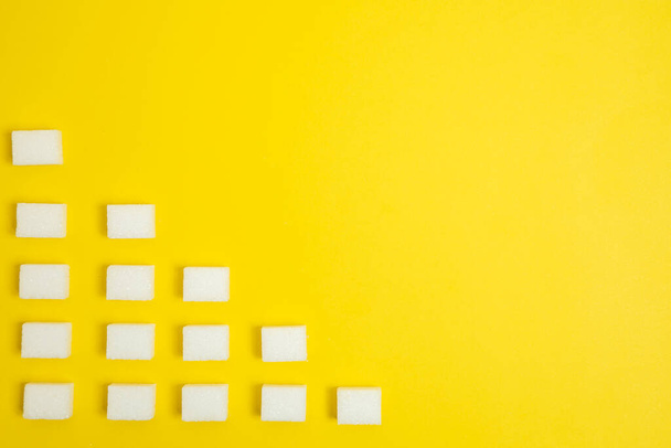 terrones de azúcar dispuestos en un triángulo con un bonito fondo amarillo - Foto, imagen