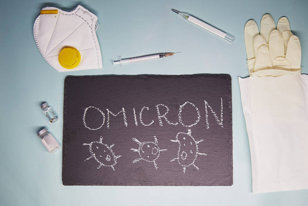 New Variant of the Covid-19 Omicron B.1.1.529 text. Face mask, vaccine, gloves, syringe and thermometer. Omicron variant of coronavirus. Chalk text on blackboard. - Photo, Image