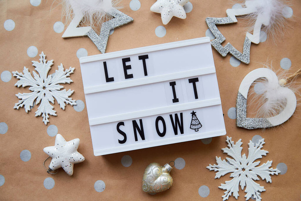 Let it snow text around Christmas ornaments. Christmas decorations on dot basic beige and golden background. Christmas mood - Photo, Image