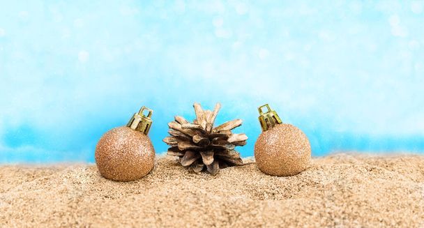 Shiny balls with pine cone on the beach. Concept for Christmas, New Year, Beach Party. Copy space - Fotoğraf, Görsel