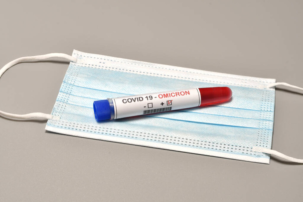 Blood tube for test detection of virus Covid-19 Omicron Variant with positive result on protection mask. Concept of protection from new variant of Omicron Covid-19 - Photo, Image