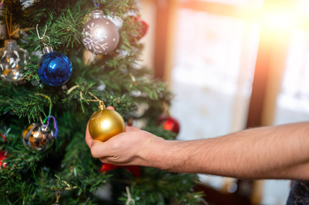 Kerstmis komt eraan: Conceptuele afbeelding van de hand van een blanke jongen grijpen een decoratieve boom bauble. - Foto, afbeelding