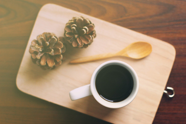 koffie en lepel op houten dienblad met dennenappel - Foto, afbeelding