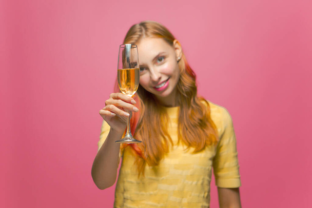 Happy young girl holding glass with champagne, celebrating holiday event, congratulating, partying on pink background - Φωτογραφία, εικόνα