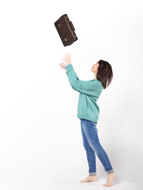 Podnikavá mladá žena v džínách a svetru s koženým kufříkem - Fotografie, Obrázek
