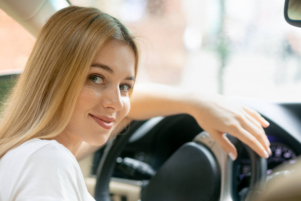Feliz joven mujer conduciendo un coche caro sonriendo. - Foto, imagen