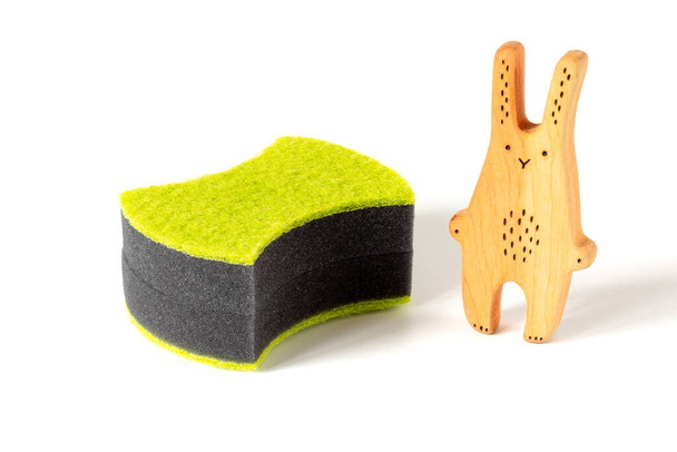 Дерев'яний іграшковий кролик і дві чорні губки для миття посуду та інших домашніх або домашніх потреб. Концепція залучення дітей до домашньої роботи, прибирання дитячого садка, догляд за тваринами
 - Фото, зображення