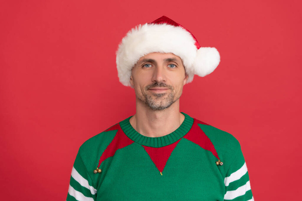 hombre feliz disfrazado de elfo. chico de Navidad en sombrero de Santa Claus sobre fondo rojo. feliz año nuevo. - Foto, imagen