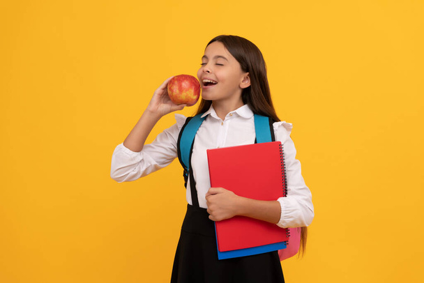 Koulutuksen hedelmä on makea. Lapsi syö omenoita koulun kirjoissa. Ruokavalistusta. Kouluvälipala - Valokuva, kuva