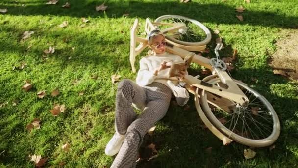γυναίκα διαβάζει ένα βιβλίο με ξύλινο οικολογικό ποδήλατο - Πλάνα, βίντεο