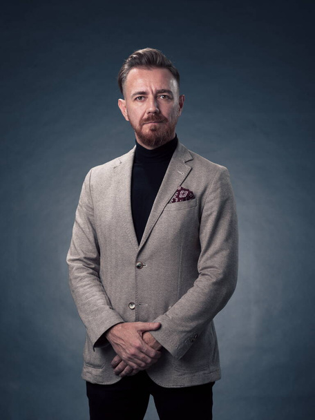 Portrait of a successful stylish elegant senior businessman with a grey beard and casual business clothes confident in photo studio isolated on dark background gesturing with hands. High-quality photo - Foto, immagini