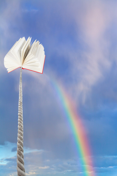 book tied on cord soars into sky with rainbow - Photo, Image