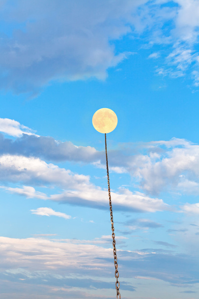 повний місяць, прив'язаний на ланцюзі, занурюється в блакитне небо
 - Фото, зображення