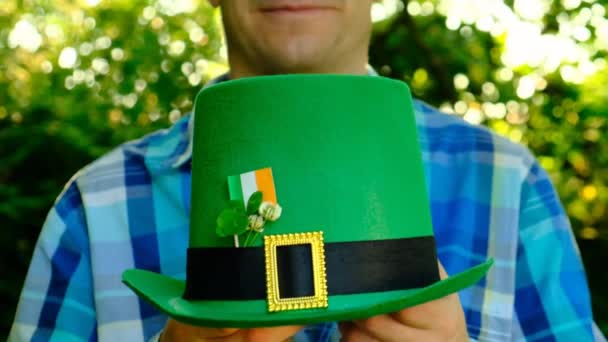 Svatý Patrik.Detailní záběr na zelený klobouk v ruce muže ve slunné jarní zahradě.Čtyřlístek jetele. Hodně štěstí symbol.Irish tradiční jarní prázdniny - Záběry, video