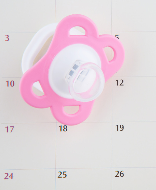 roze fopspeen en kalender - Foto, afbeelding