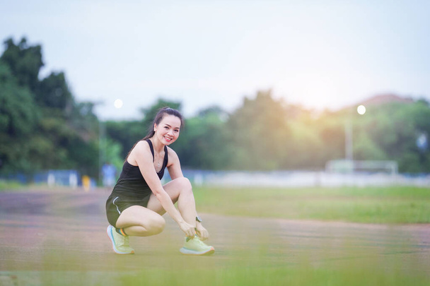 Egy érett gyönyörű ázsiai nő sport ruhák nyújtózkodik edzés előtt szabadtéri a városi stadion parkban reggel, hogy egy egészséges életmódot. Egészséges fiatal nő melegszik a szabadban - Fotó, kép