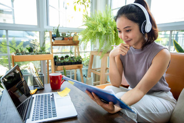 Ázsiai üzletasszonyok használ notebook számítógépek és visel fülhallgatót az online találkozók és a munka otthonról. - Fotó, kép