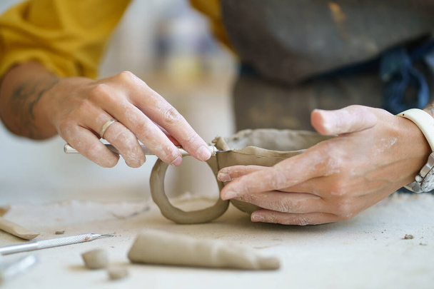 土コップを成形する女性陶芸家。プロの陶芸家の手は、ワークショップで陶器の食器を作成します。 - 写真・画像